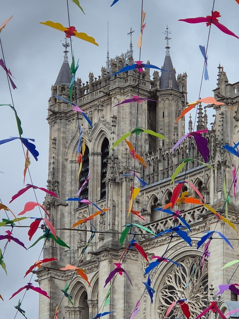 Vue d'une cathédrale avec des décorations colorées en forme d'oiseaux suspendues dans l'air.