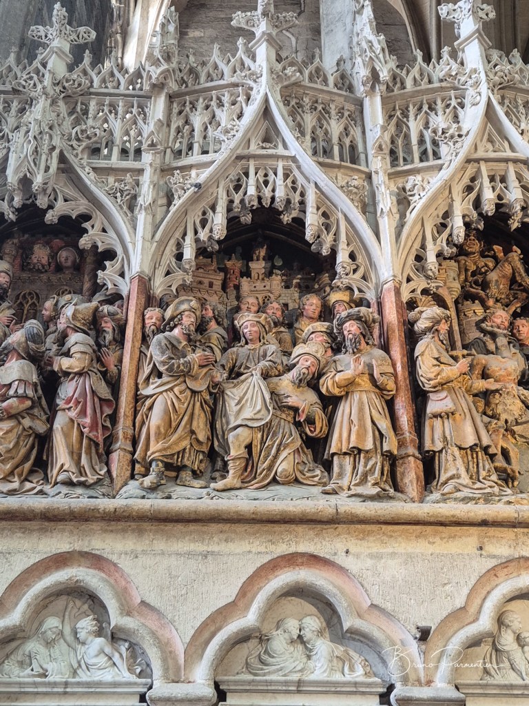 Détails sculptés d'un retable religieux présentant des figures humaines en médaillons, avec une ornementation complexe en arrière-plan.