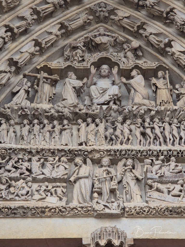 Scène sculptée représentant des figures religieuses, y compris Jésus et des anges, sur la façade d'une cathédrale.